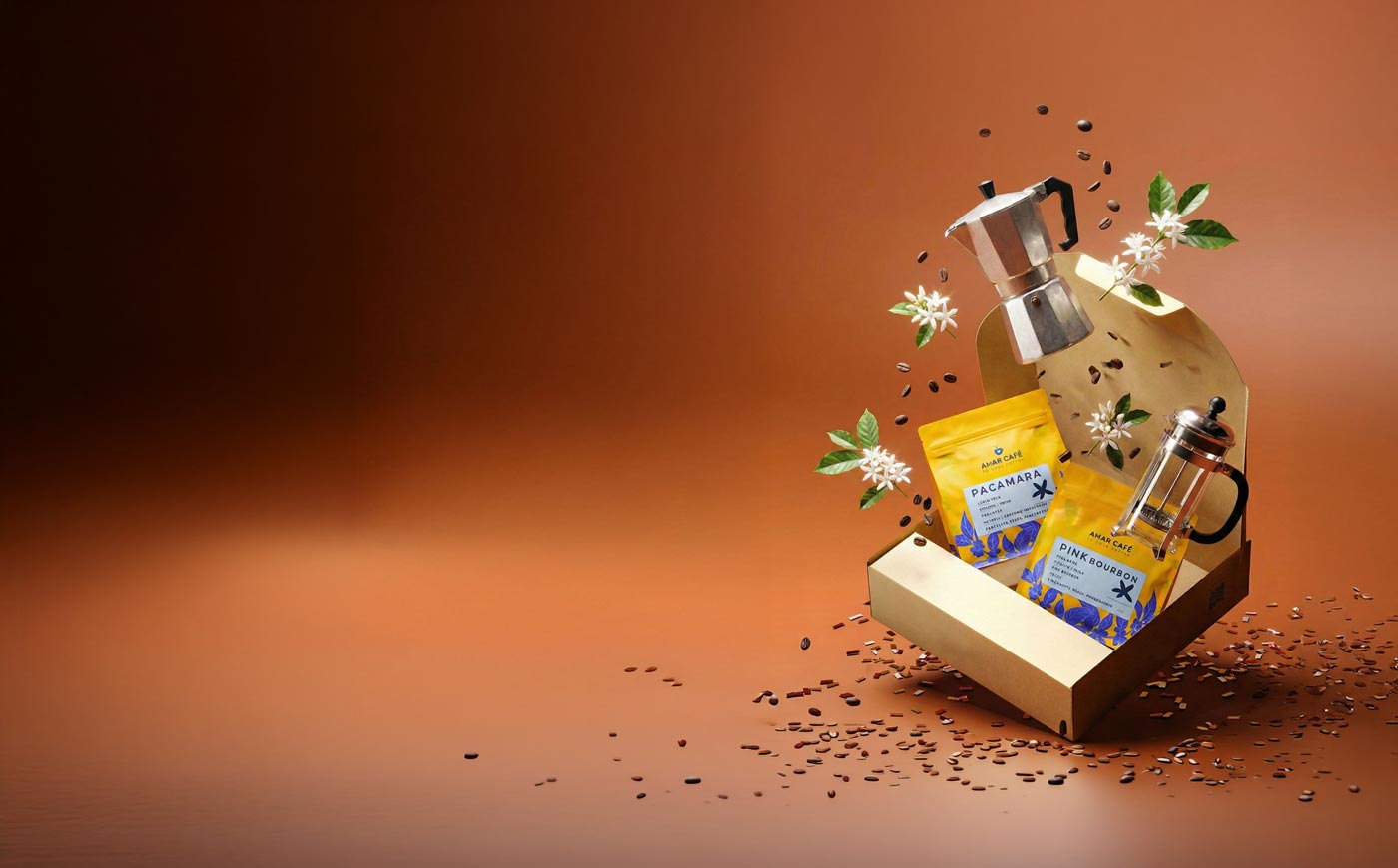 Caja de regalo con bolsas de Amar Café, cafetera italiana y prensa francesa sobre fondo cobre