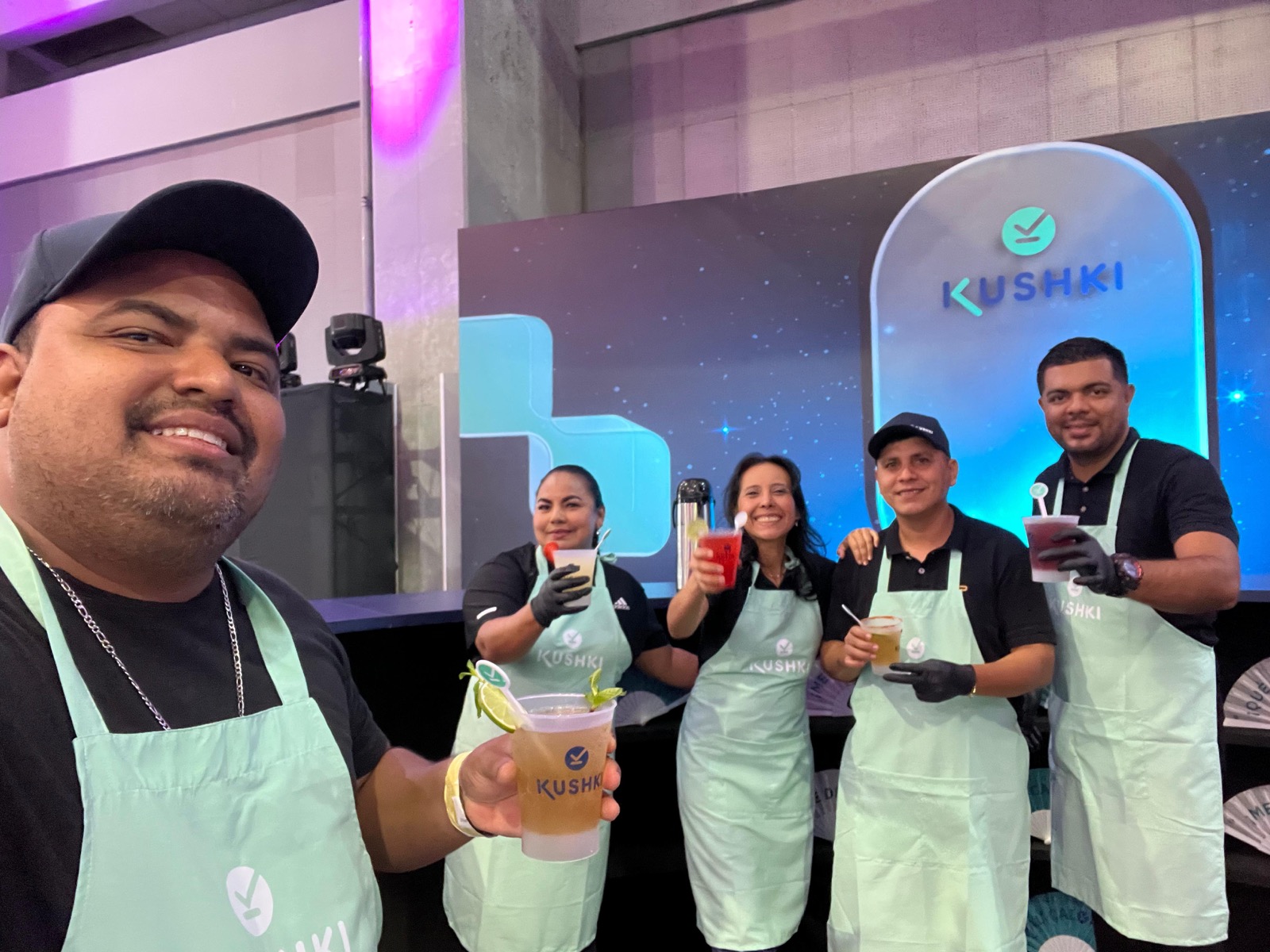 Equipo de bartenders de Experiencia VINTO brindando con bebidas frías en la barra del stand de KUSHKI en Barranquilla