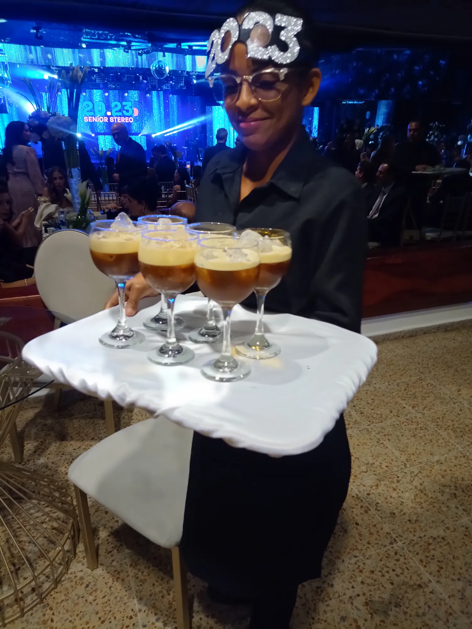 Integrante del equipo de servicio con una bandeja de cócteles de café en copas durante una fiesta de noche