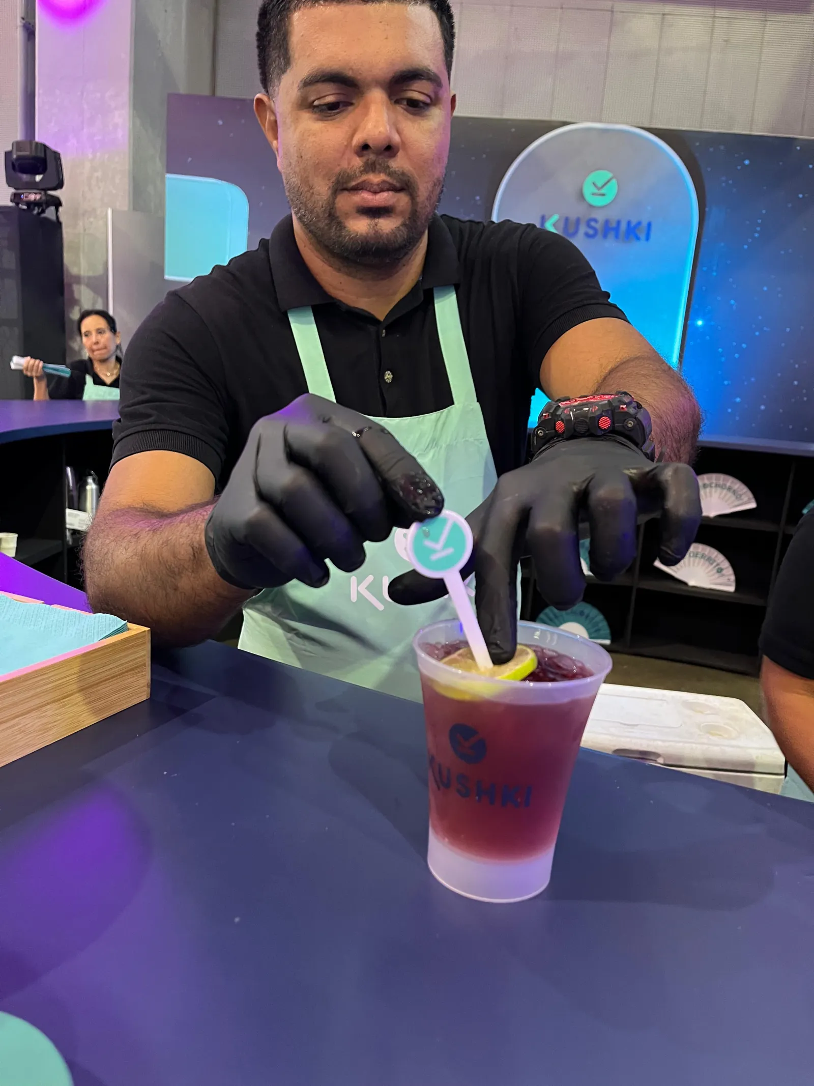 Bartender con guantes decorando un cóctel en vaso con hielo durante un evento corporativo