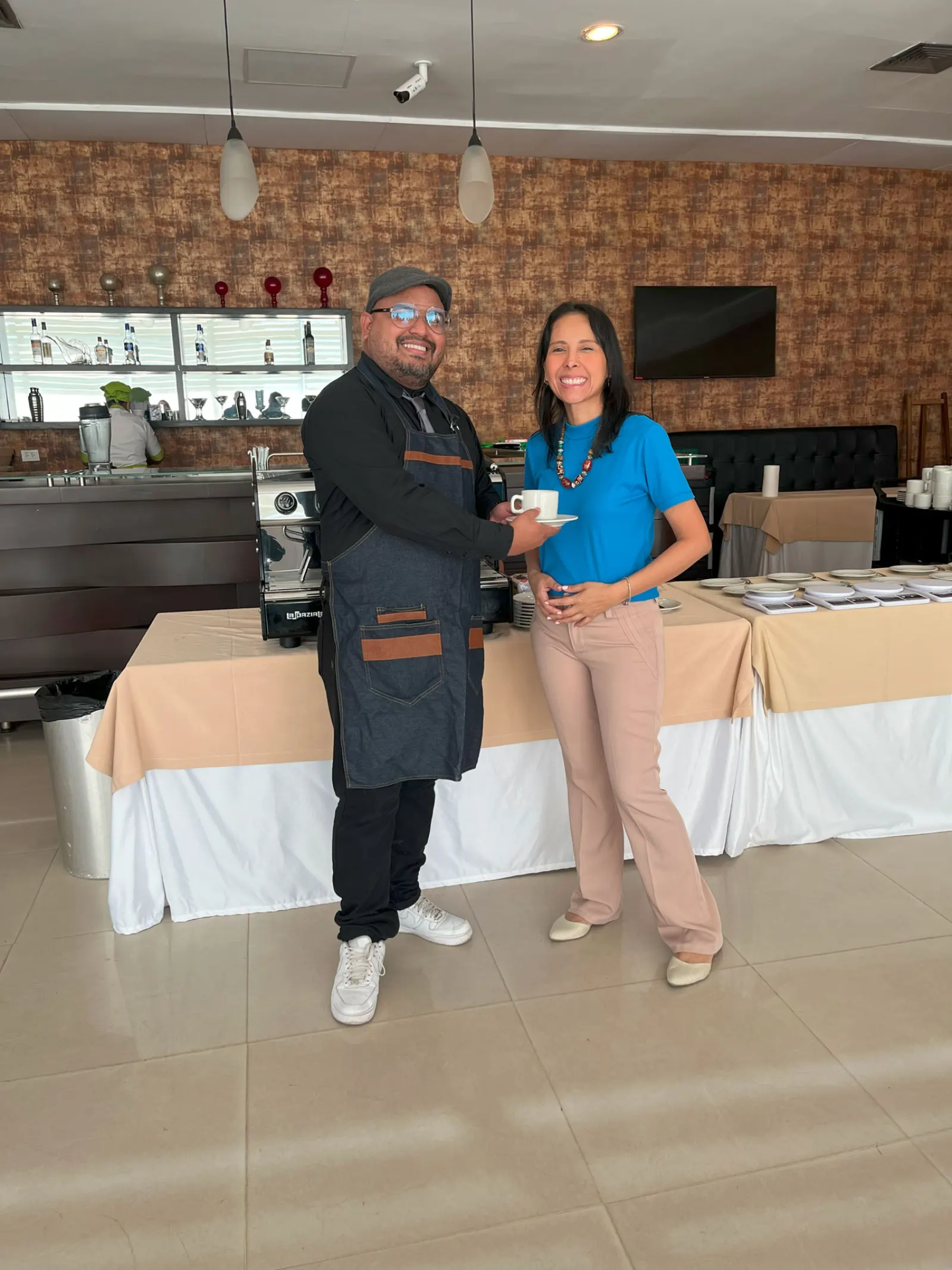 Barista y colaboradora con una taza de café durante una actividad de bienestar en una empresa