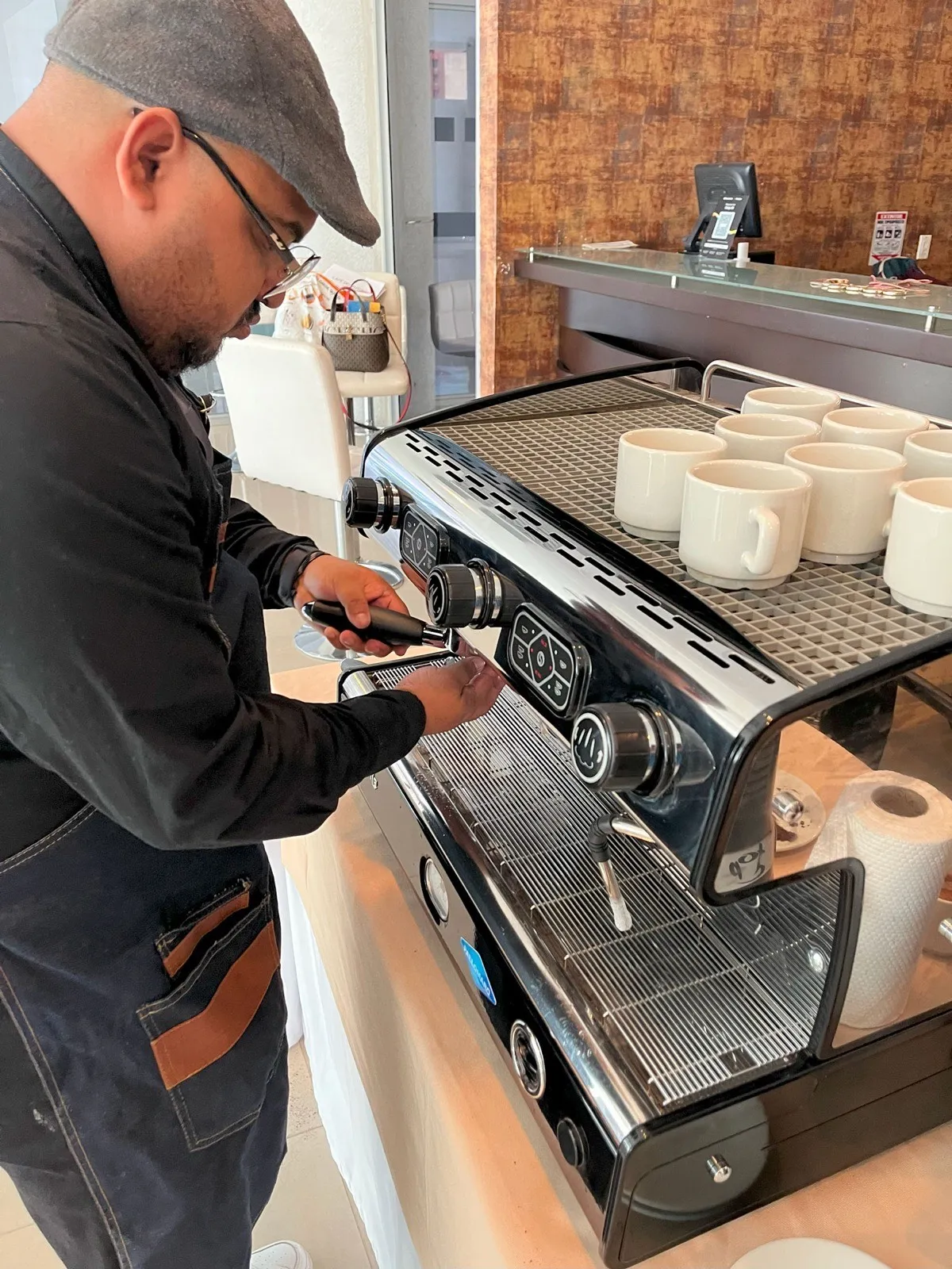 Barista de Experiencia VINTO preparando espresso en una máquina profesional con tazas blancas sobre la bandeja durante una cata de café