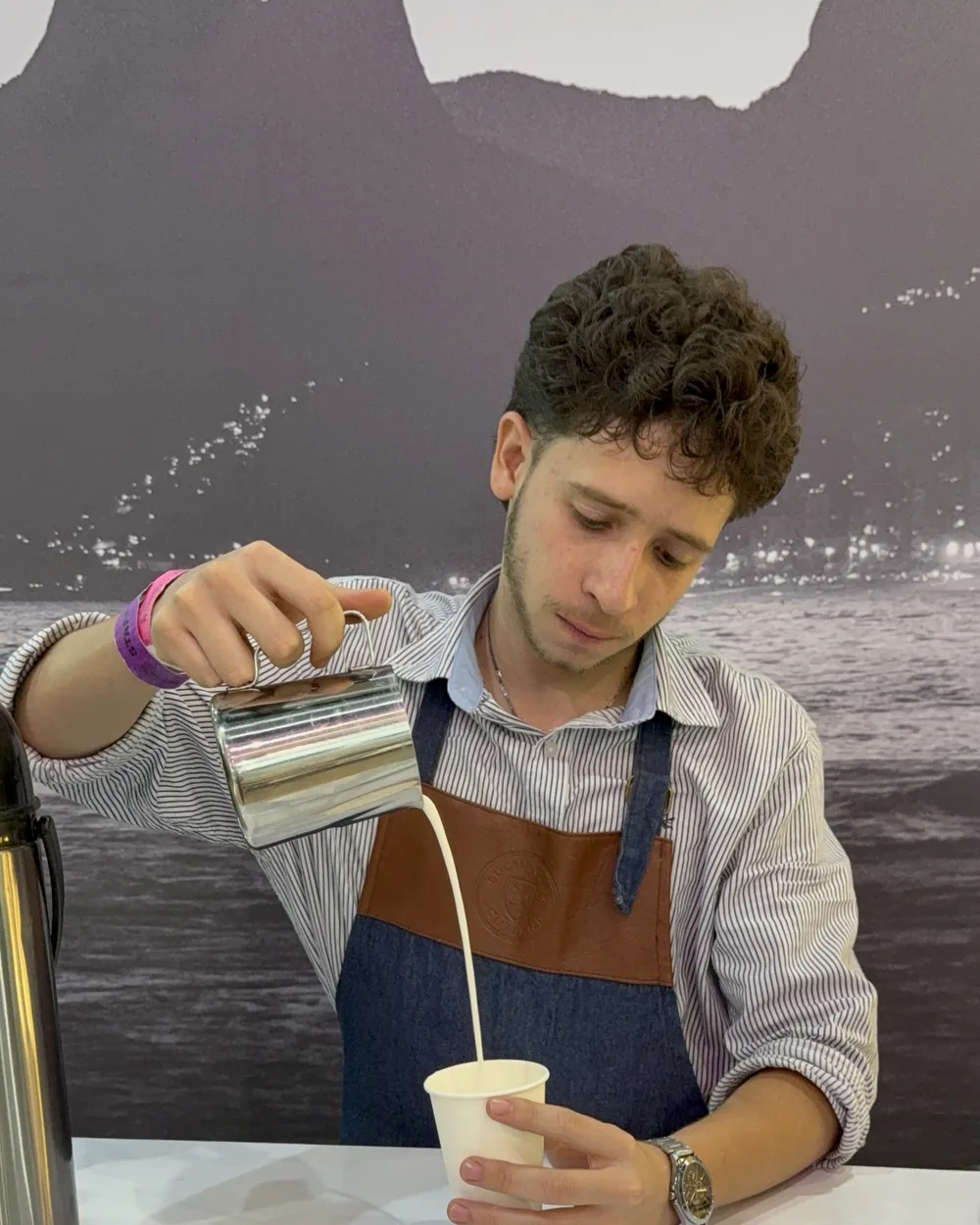 Barista de Experiencia VINTO vertiendo leche vaporizada en un vaso durante el servicio de una estación de café