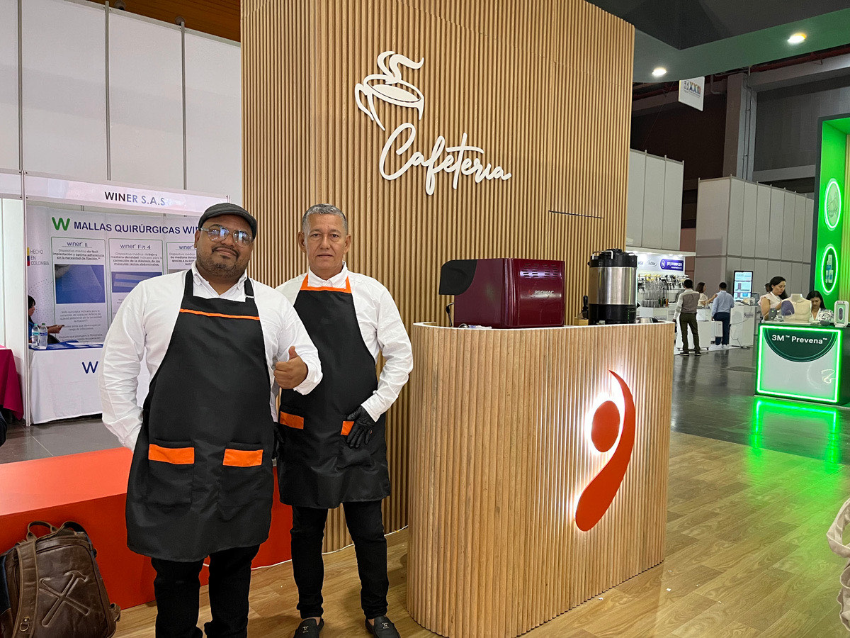 Dos baristas de Experiencia VINTO junto a la estación de café con máquina de espresso en un congreso médico