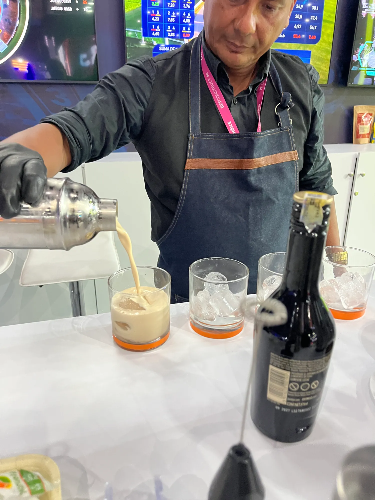 Barista pouring iced coffee drinks from a shaker at a trade show booth in Cartagena
