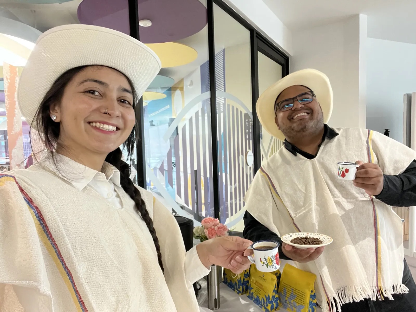 Equipo de Experiencia VINTO con ruana y sombrero mostrando una taza de café y un plato con granos de café