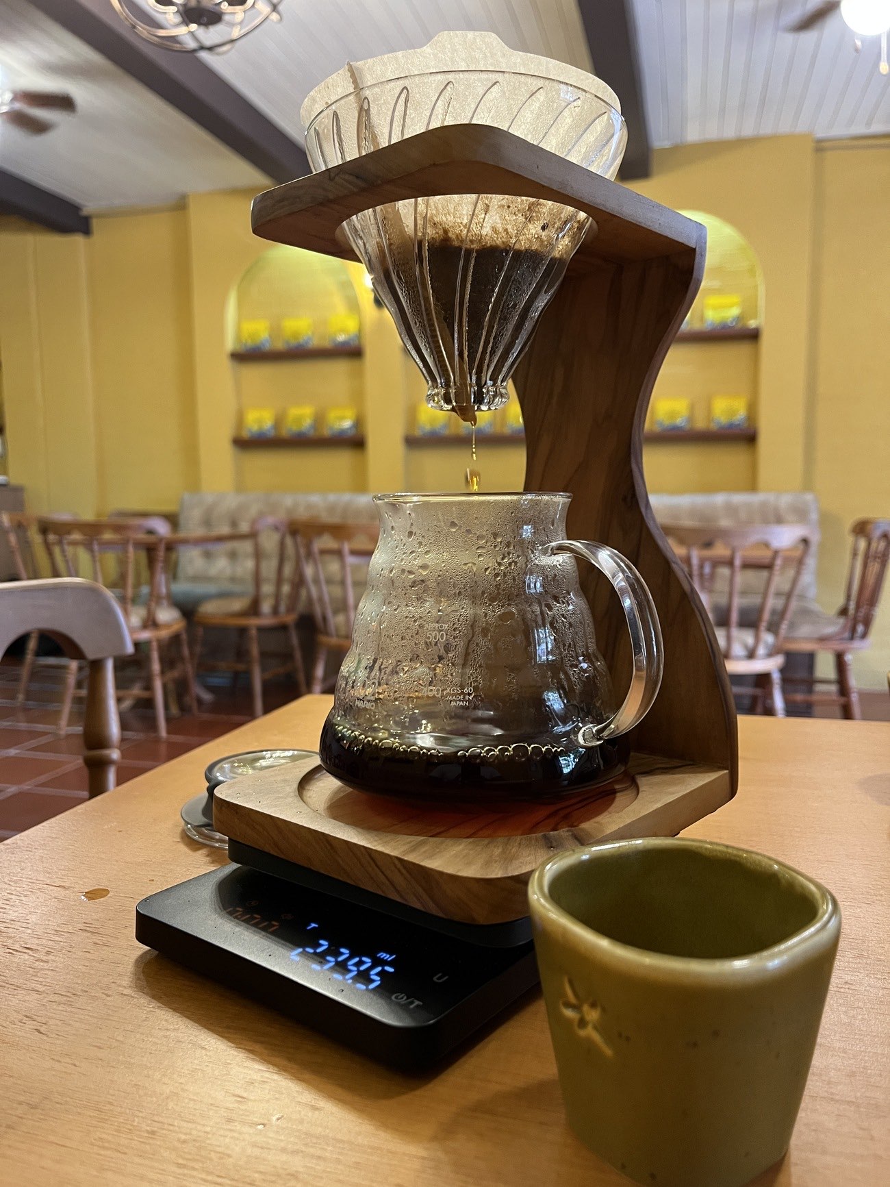 Café filtrado en V60 sobre una base de madera, con jarra de vidrio y báscula digital