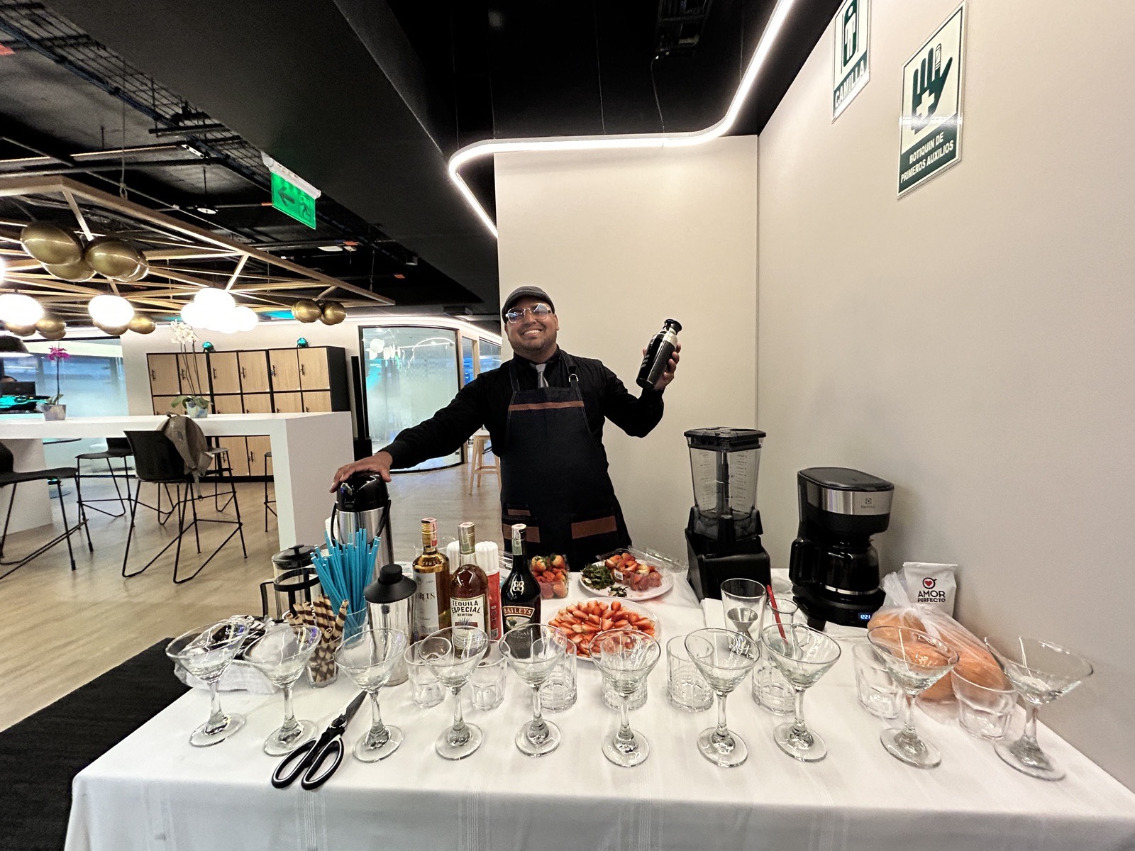 Barra de bebidas para el cierre de una jornada corporativa en oficina, con café, frutas y copas listas para servir