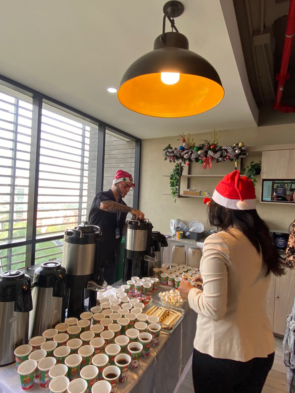 Coffee break en oficina con termos, vasos para cada asistente y snacks dulces sobre la mesa de servicio