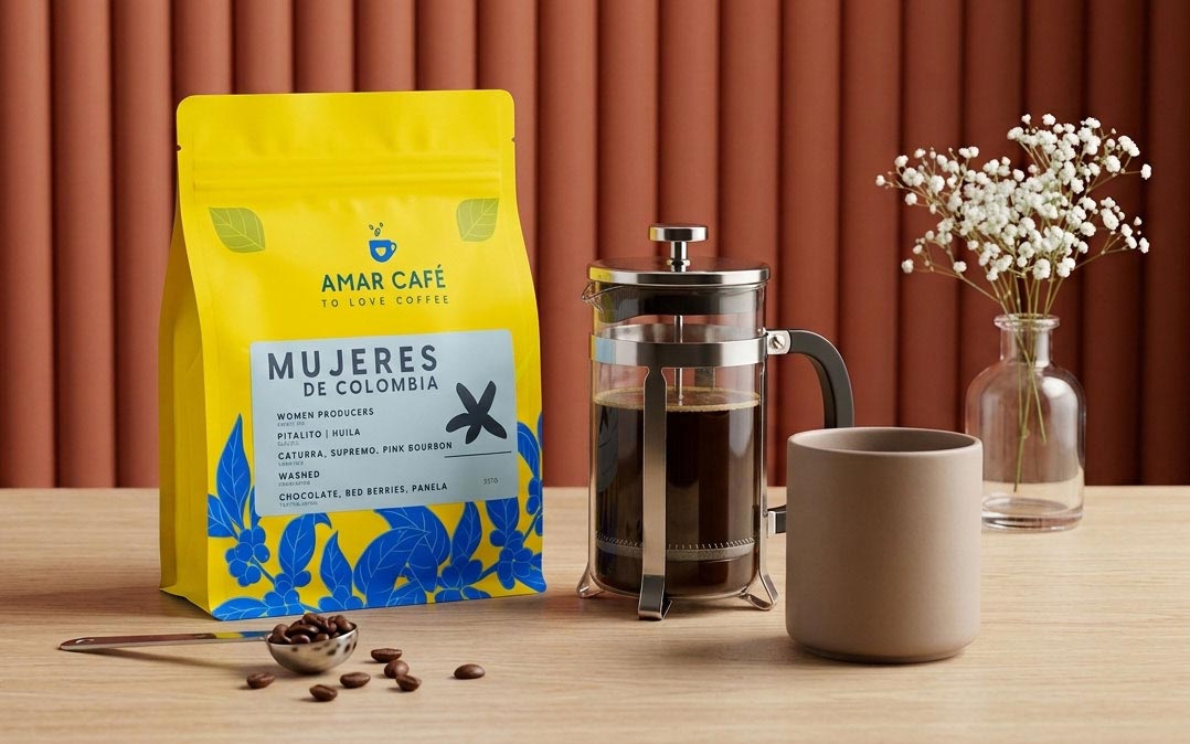 Kit de café con bolsa de Amar Café Mujeres de Colombia, prensa francesa y mug sobre mesa de madera